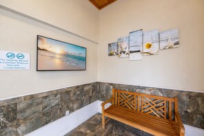Un banc placé dans un coin, adossé à un mur de pierre, avec un tableau représentant une scène de plage.
