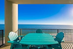 A covered outdoor seating area with a table and chairs, overlooking the ocean.