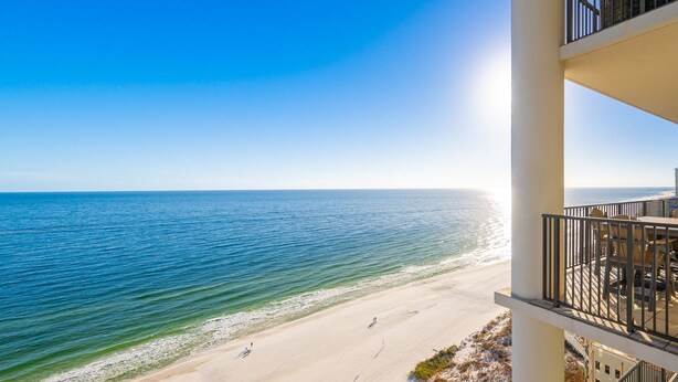 A beachfront hotel balcony with a view of the ocean and beach.
