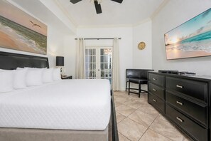 A hotel room with a bed, a desk, a chair, a dresser, and two paintings.