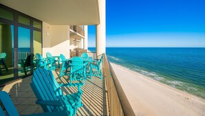 A balcony with turquoise chairs and a view of the ocean.