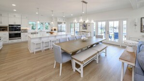 Una cocina amplia con armarios blancos, una isla grande y un comedor con una mesa de madera y bancos.