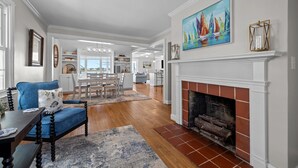 A spacious living room with a fireplace, a dining area, and a kitchen in the background. - NEWLY RENOVATED Sound Front Home with Dock in Downtown Beaufort, NC (Creek Watch) (Beaufort)