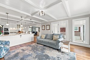 A spacious living area with a sofa, a coffee table, and a kitchen in the background. - NEWLY RENOVATED Sound Front Home with Dock in Downtown Beaufort, NC (Creek Watch) (Beaufort)
