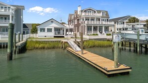 A waterfront property with a dock, a house with a balcony, and a sign indicating rental availability. - NEWLY RENOVATED Sound Front Home with Dock in Downtown Beaufort, NC (Creek Watch) (Beaufort)