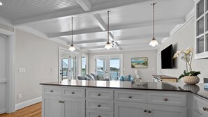 A spacious kitchen with white cabinetry, a large island, pendant lighting, and a view of the outdoors. - NEWLY RENOVATED Sound Front Home with Dock in Downtown Beaufort, NC (Creek Watch) (Beaufort)