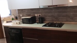 Een moderne keuken met witte kastjes, een ingebouwde magnetron, een gasfornuis en een vaatwasser.