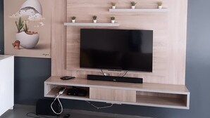 Een moderne woonkamer met een grote flatscreen televisie bevestigd aan een houten wand, omringd door planken met kleine planten.