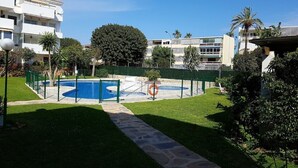 A residential area with a swimming pool, a stone pathway, and surrounding greenery.