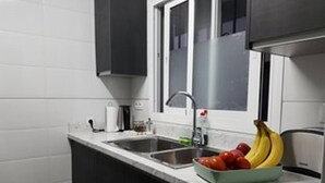 A kitchen with a sink, a window, and a fruit bowl containing bananas and apples.