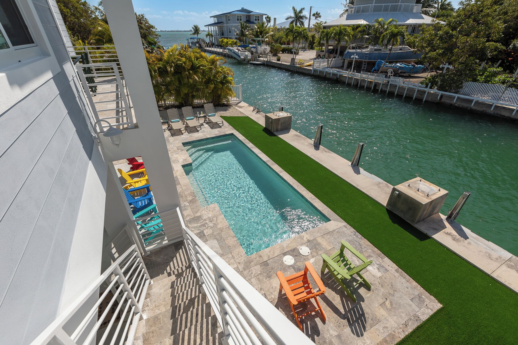 A pool area with a rectangular pool, green artificial turf, and lounge chairs.