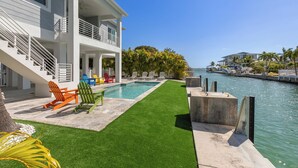 A modern house with a pool, outdoor seating, and a view of the water. - ARTIST HOUSE ~ Canal Front 4 BR/3.5 Ba Home w/ Pool & Ocean and Gulf Access! (Cudjoe Key)