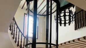 A modern interior with a spiral staircase, a glass elevator, and a reception desk. - Hotel A Posada (Tembleque)