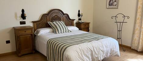 A neatly made bed with a striped bedspread, wooden nightstands with lamps, and a wall-mounted picture.