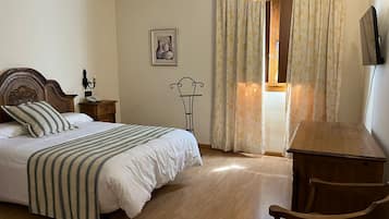 Un dormitorio con cama de madera, una mesita de noche, una silla y una ventana con cortinas.