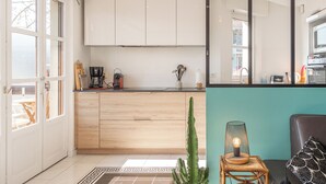 A modern kitchen with white cabinets, a coffee machine, and a cactus plant.