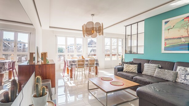 A spacious living room with a sofa, coffee table, and dining area with chairs.