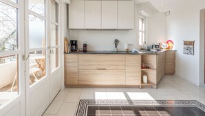 A modern kitchen with wooden cabinets, a black countertop, and a view of the outdoors through large windows.