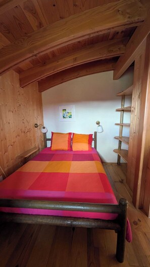 A cozy attic bedroom with a wooden bed, a slanted ceiling, and a wooden ladder. - Hobbit" gîte (Limbrassac)