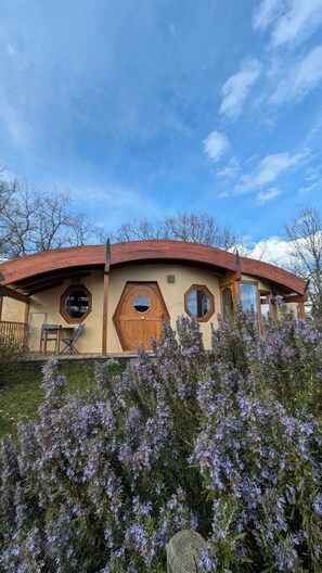 Un bâtiment unique, doté d’un toit incurvé, de fenêtres octogonales et d’une porte en bois.