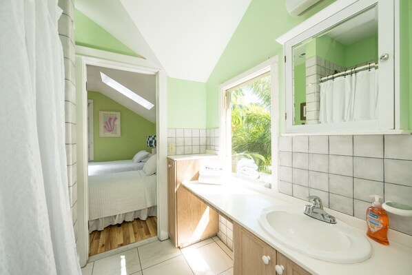 A bathroom with a sink, mirror, and shower area. - Family Reunion Compound - Great for Groups! Large pool. (Key West)