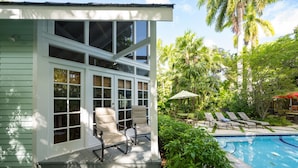 A house with a covered porch, a pool, and outdoor furniture. - Family Reunion Compound - Great for Groups! Large pool. (Key West)