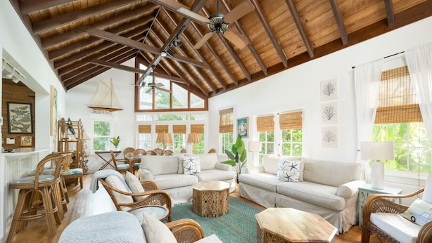A spacious living area with high ceilings, wooden beams, and large windows. There are multiple seating options including sofas and chairs. - Family Reunion Compound - Great for Groups! Large pool. (Key West)