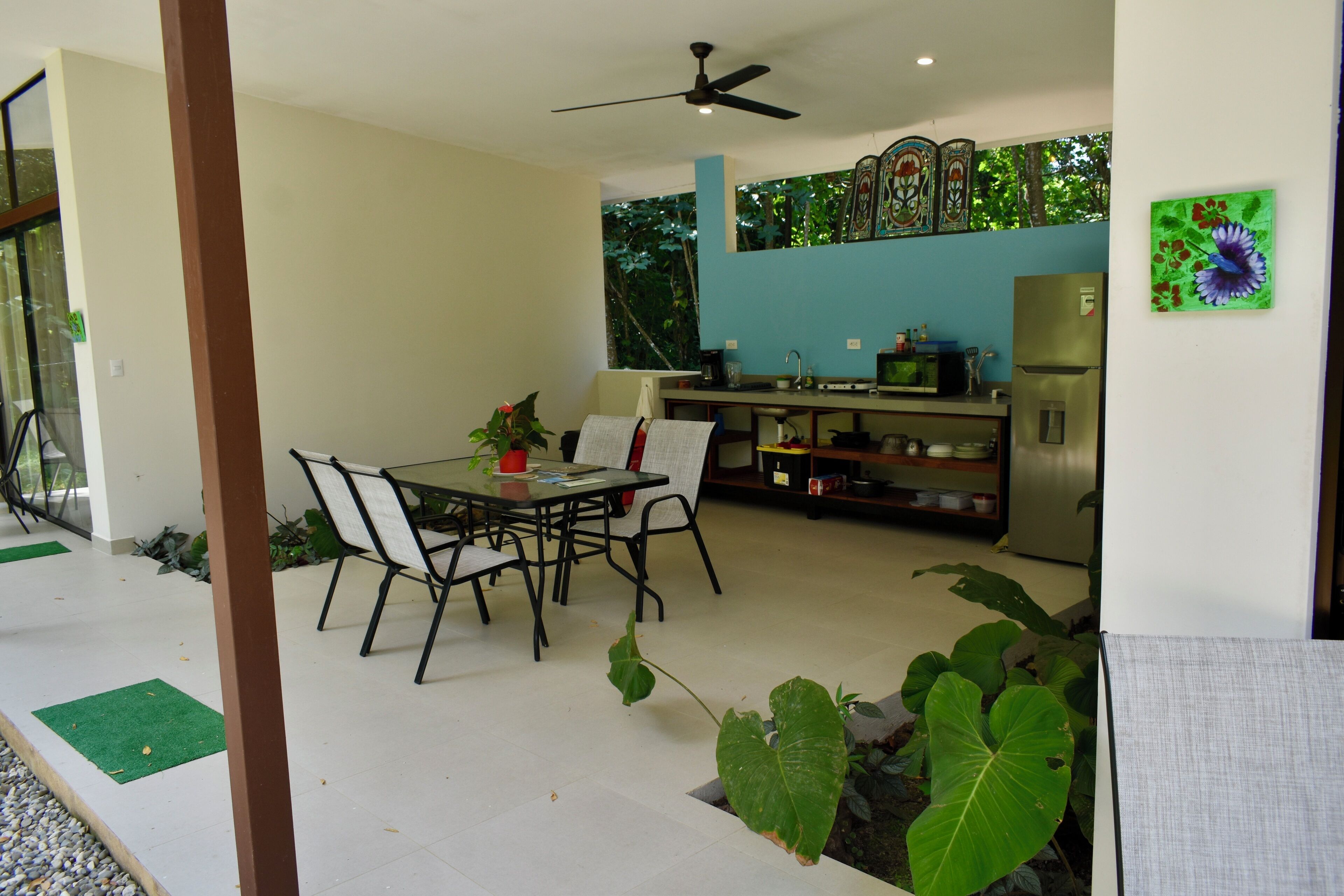 Una cucina moderna con zona pranzo, dotata di ventilatore a soffitto, frigorifero e tavolo con sedie.