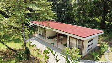 Ein modernes Haus mit rotem Dach, großen Fenstern und einer überdachten Terrasse.