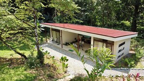 A modern house with a red roof, a covered patio, and a gravel driveway. - Casa Rio Tortuga - 2 Bedrooms with Outdoor Dining Area (Ojochal)