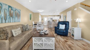 A spacious living room with a beige sofa, a blue armchair, and a wooden coffee table.
