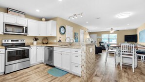 A modern kitchen with white cabinetry, stainless steel appliances, and a dining area with a wooden table and chairs.