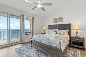 A bedroom with a large bed, two bedside lamps, a ceiling fan, a view of the ocean, and a balcony. - Treasure Island END Unit with ENDLESS Eastern Views, Huge Wrap Around Balcony (Panama City)