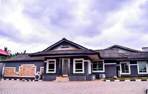 A two-story house with a tiled roof, a front porch, and a paved driveway.