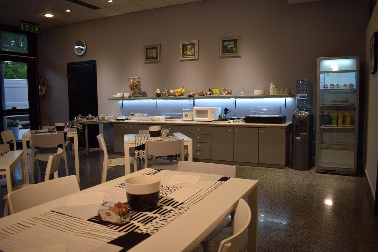 A modern kitchen with white appliances, a refrigerator, and a dining area with white chairs and tables.