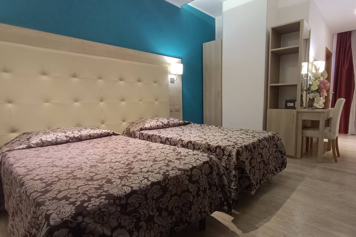 A room with two beds, a desk, and a chair.