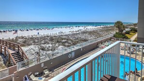 A balcony with a view of a beach and a swimming pool.