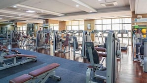 A gym with various exercise machines, benches, and a mirrored wall.