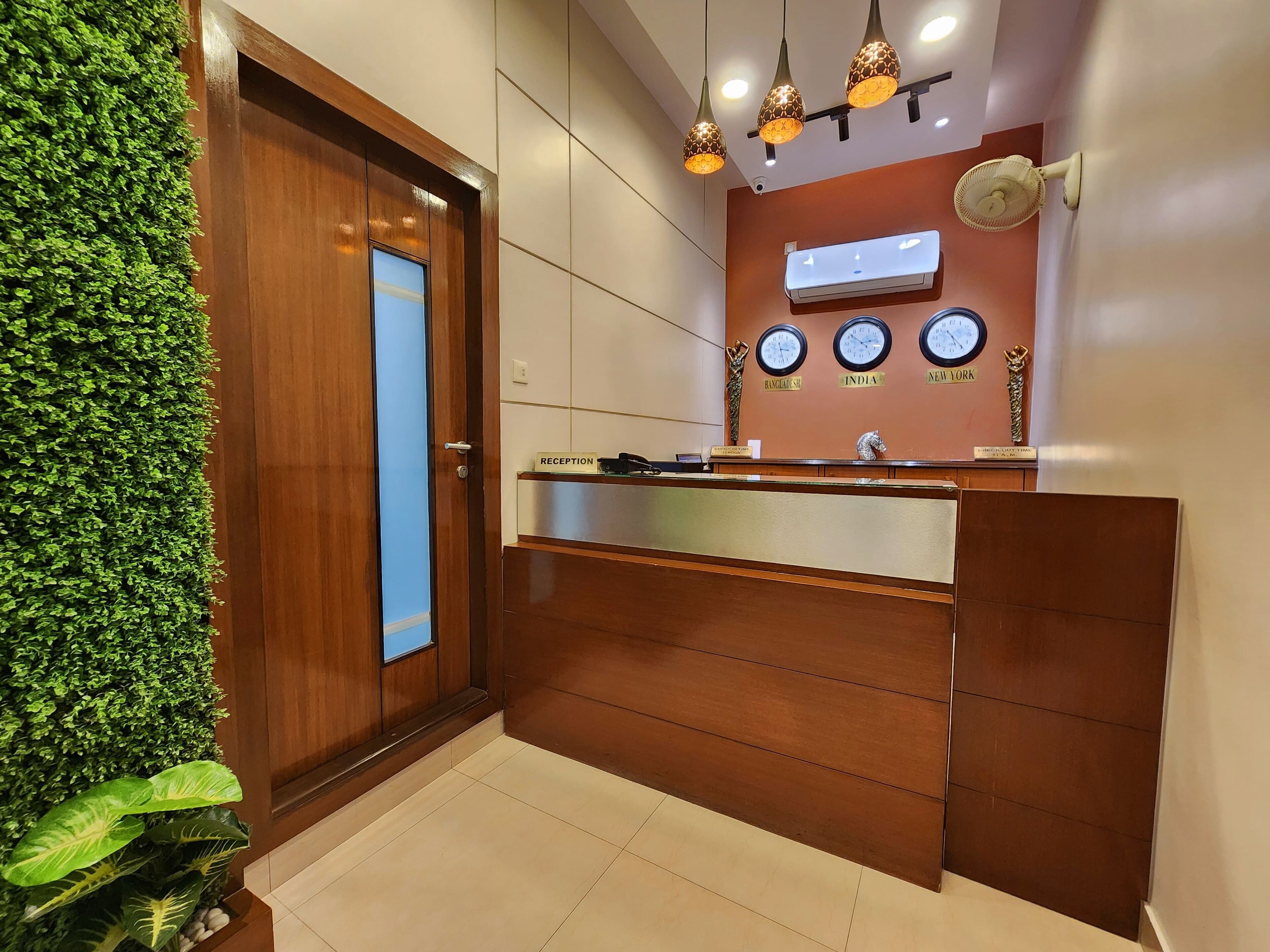 A reception area with a wooden reception desk, a wall-mounted air conditioner, and three clocks displaying different time zones.