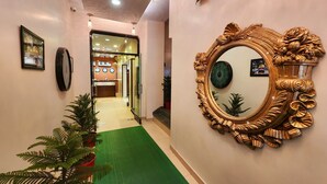 A hotel hallway with a green carpet, a large ornate mirror, and a reception desk in the background. - HOTEL HOUSEZ43 (Kolkata)
