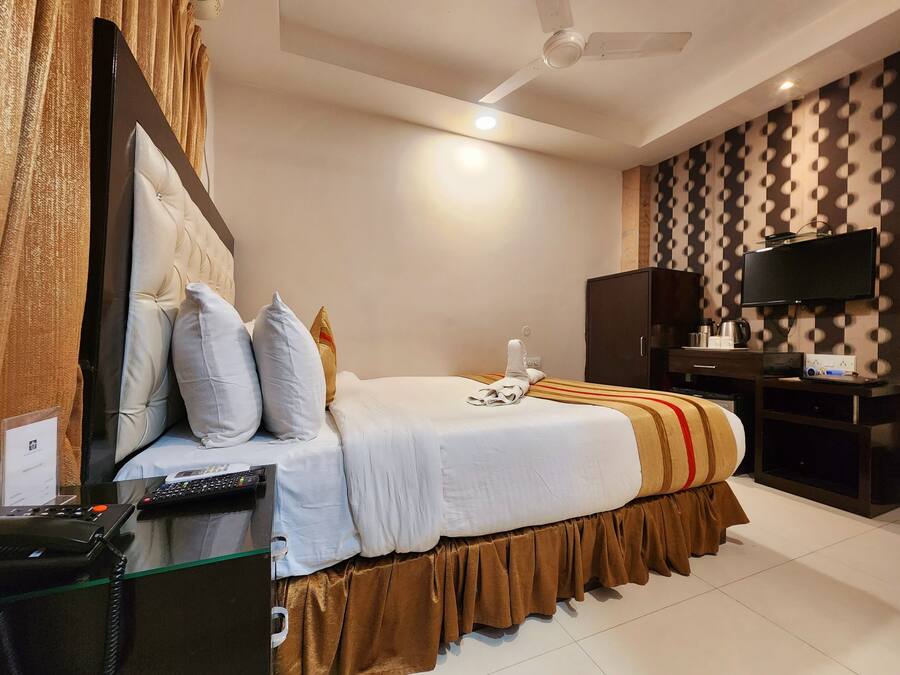 A hotel room with a bed, a desk with a computer, a television, and a wardrobe.
