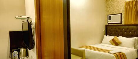 A hotel room with a bed, bedside table, and a television mounted on the wall.