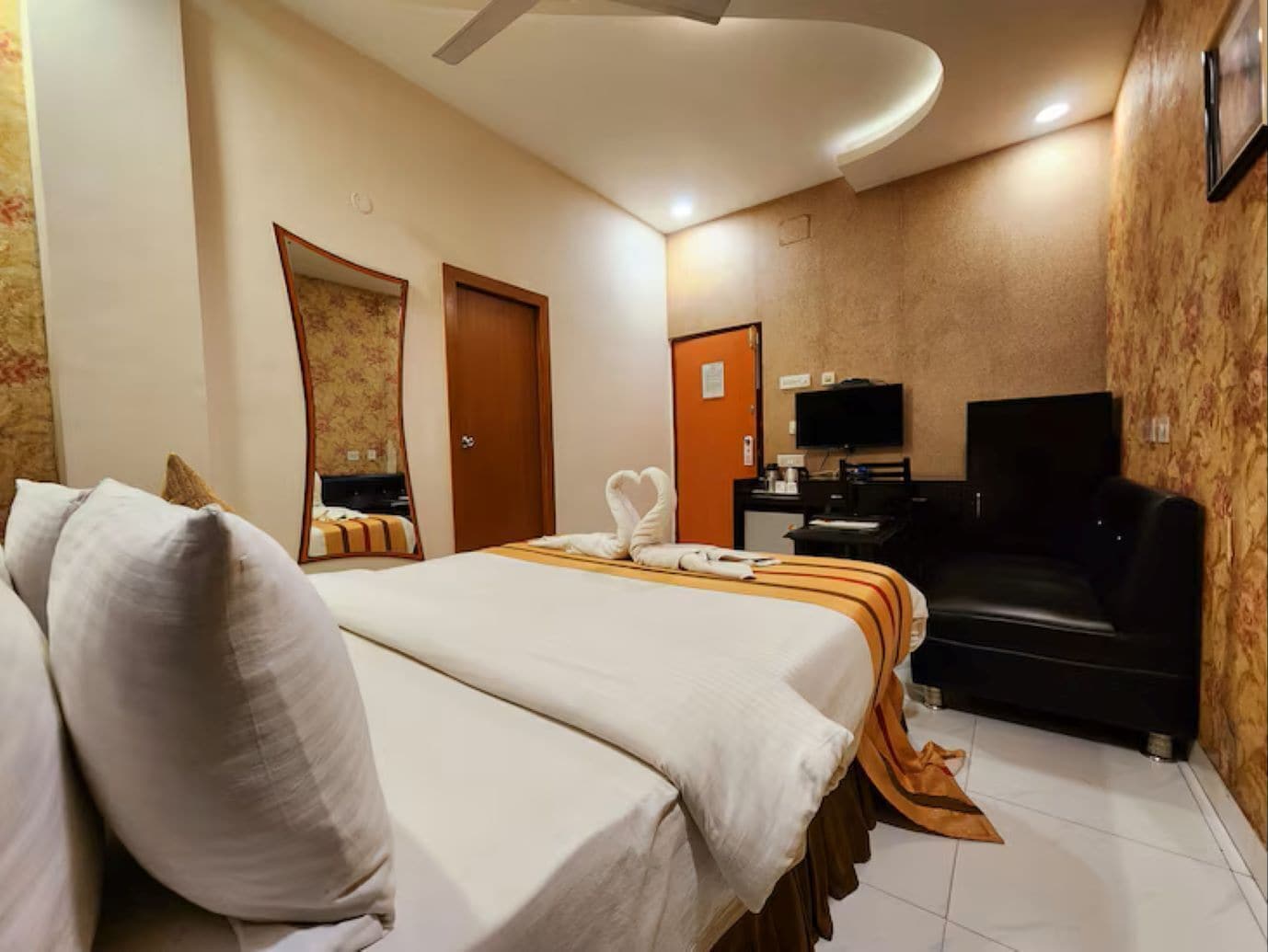 A hotel room with two beds, a TV, a desk, and a sofa.