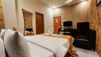 A hotel room with two beds, a TV, a desk, and a sofa.