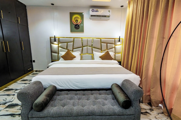 Ein Hotelzimmer mit einem großen Bett, einem Kopfteil mit geometrischem Muster, einer Wand-Klimaanlage und einem Wanddekor.