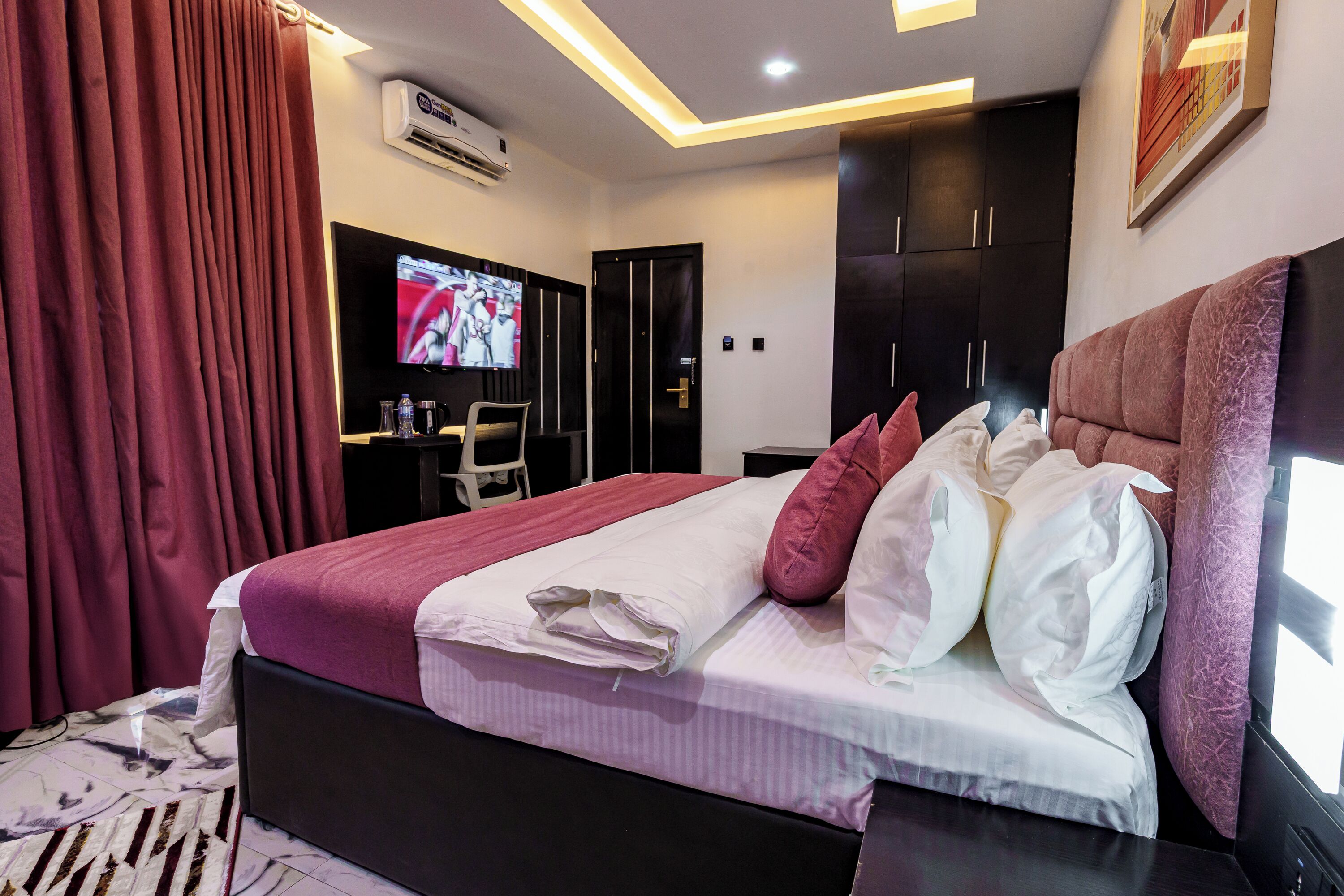 Een moderne hotelkamer met een groot bed, een flatscreen televisie, een bureau en een kledingkast.