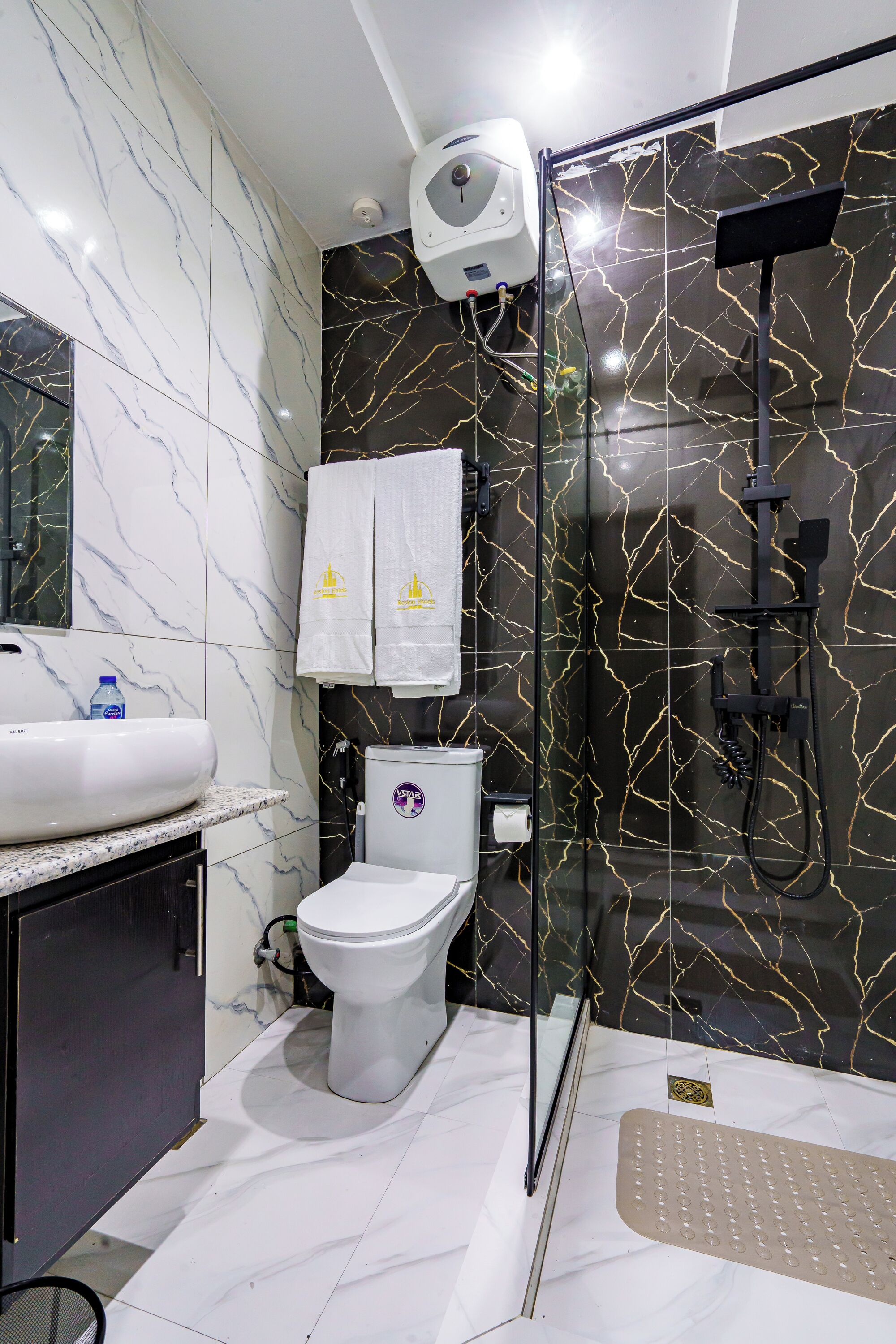 A bathroom with a glass-enclosed shower, a white toilet, a sink, and a mirror.