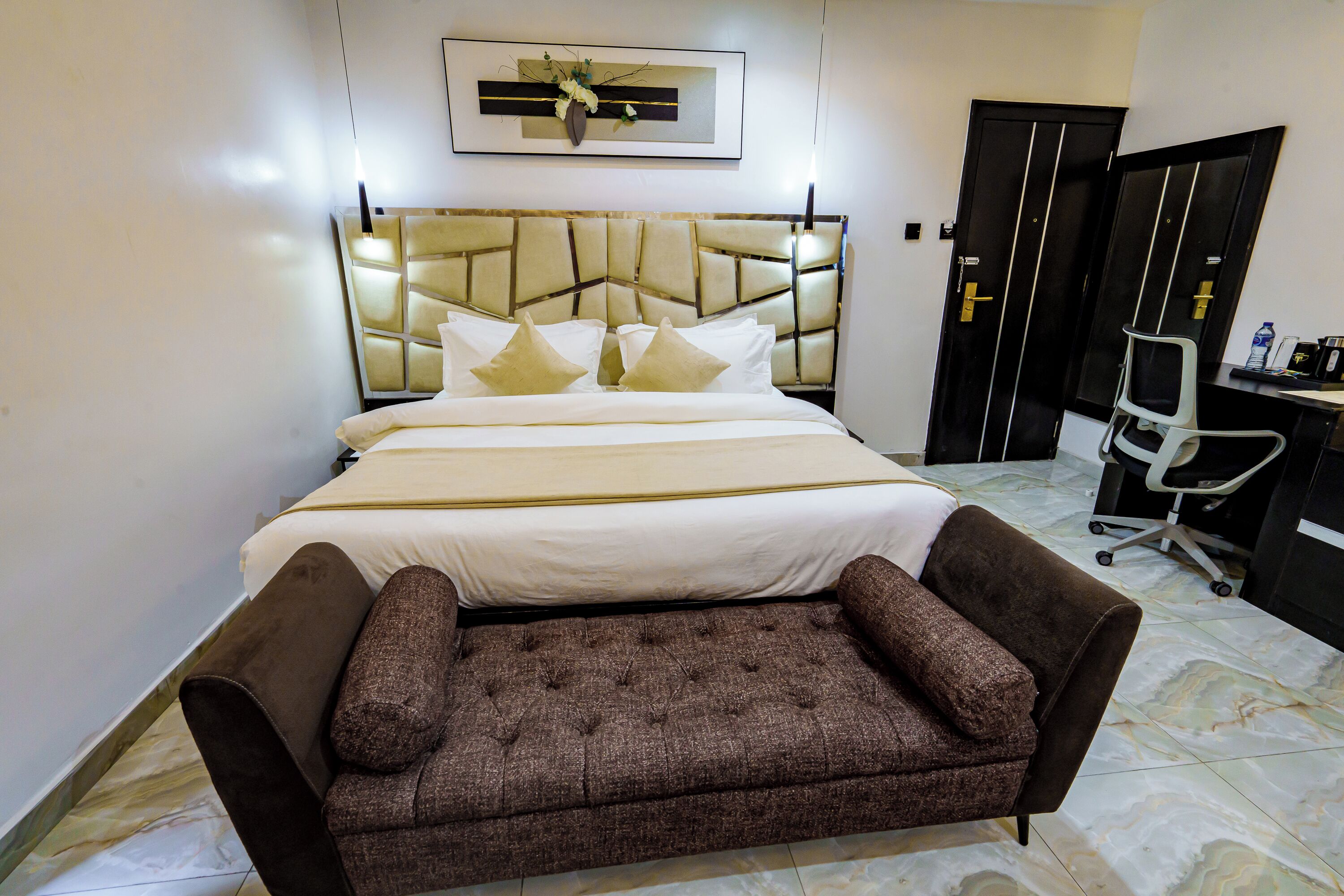 A neatly arranged bedroom with a bed, a sofa, a desk, and a chair.