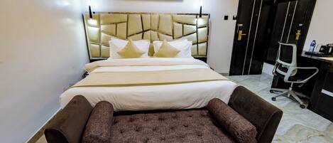A neatly arranged bedroom with a bed, a sofa, a desk, and a chair.