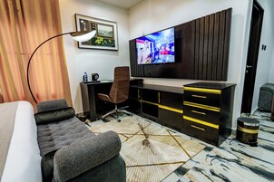 Una habitación de hotel moderna con una cama grande, un escritorio con silla, un televisor y una alfombra estampada.